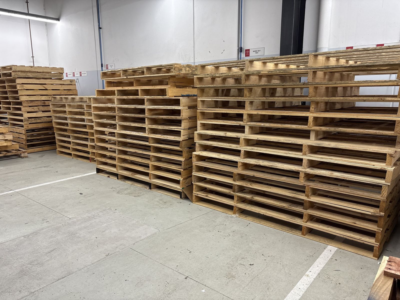 Used timber pallets stacked inside a warehouse