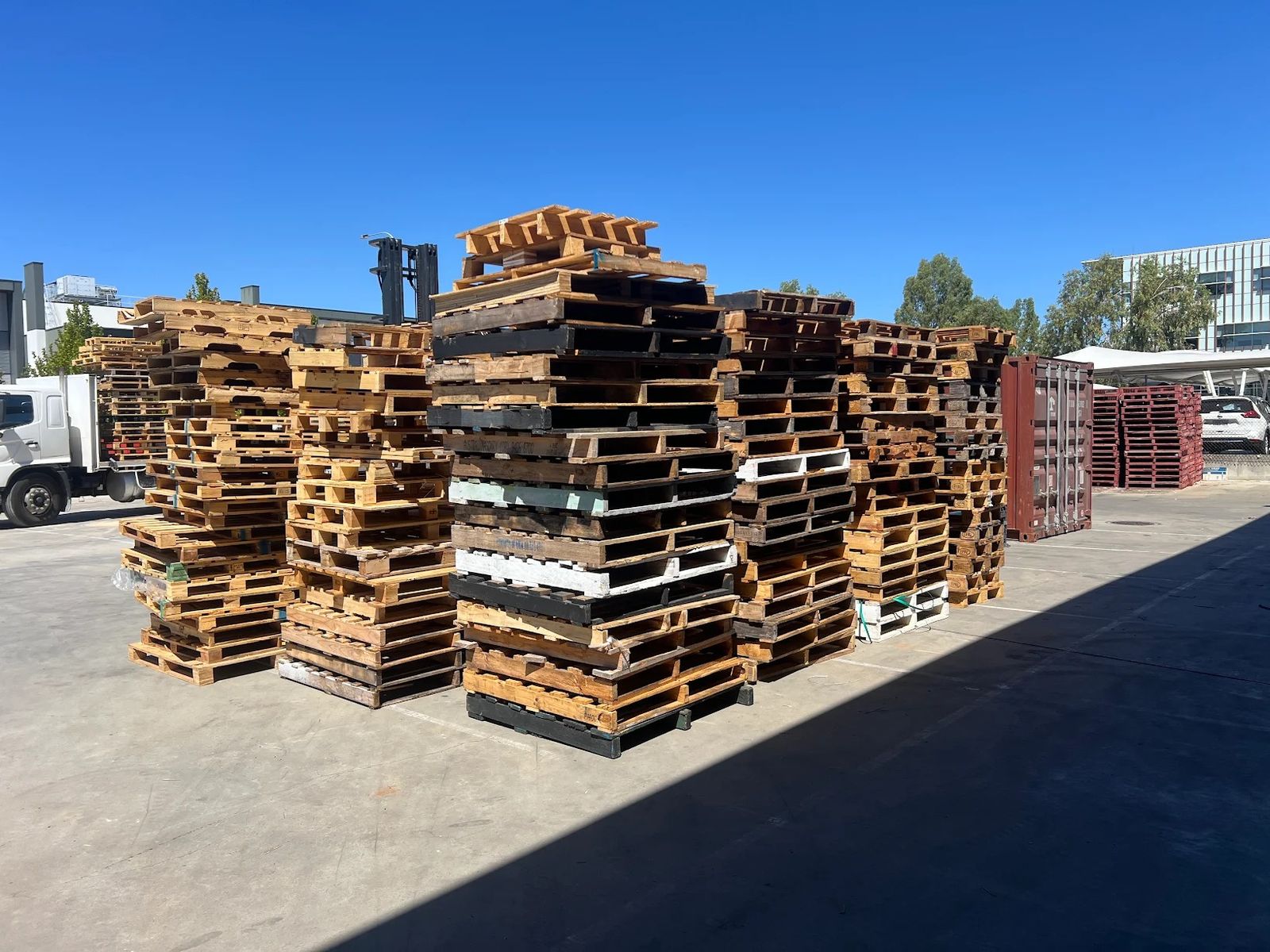 Stacks of collected used timber pallets in a yard