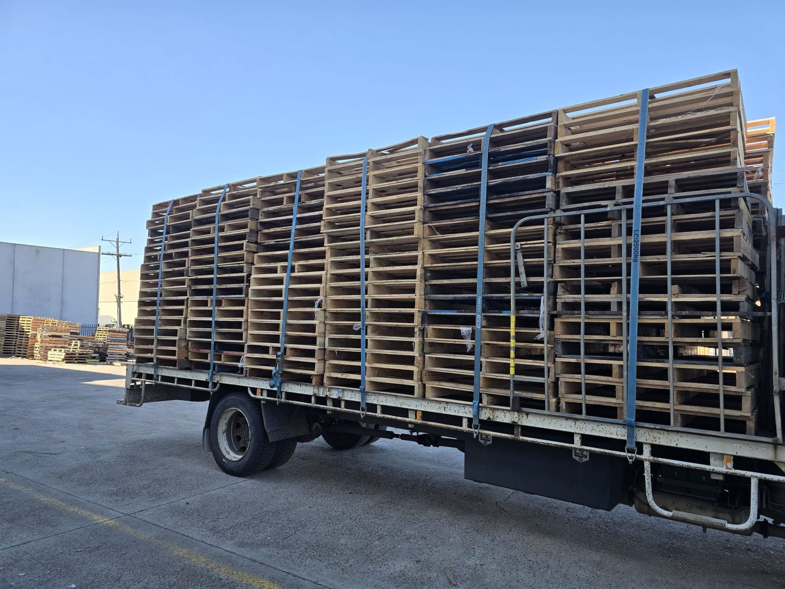 A tray truck loaded with strapped stacks of pallets collected in Melbourne
